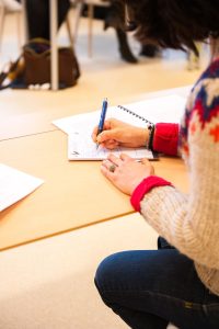 woman holding blue pen writing on paper